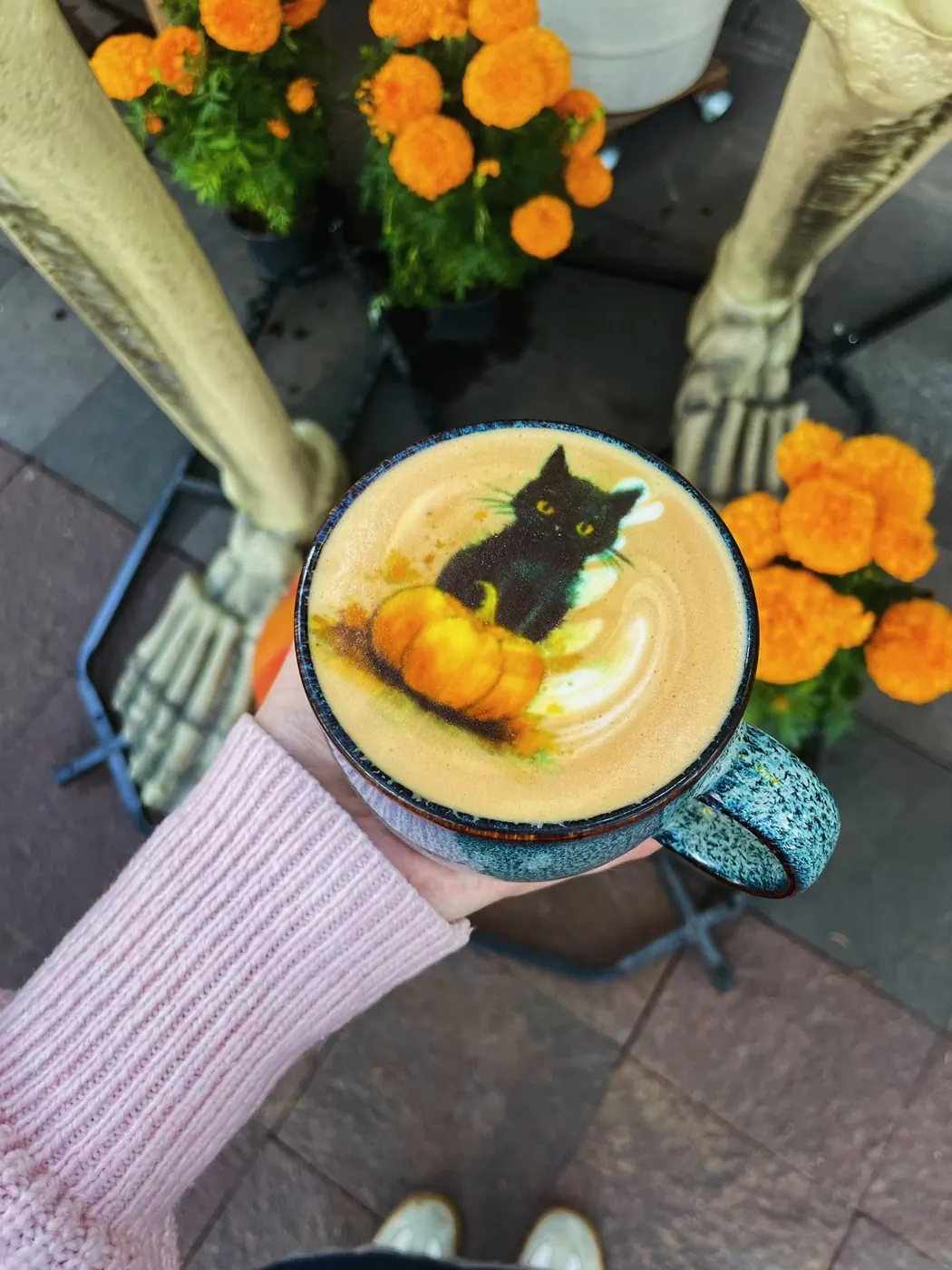 Taza con un gato negro y una calabaza impresos, entre cempasúchil