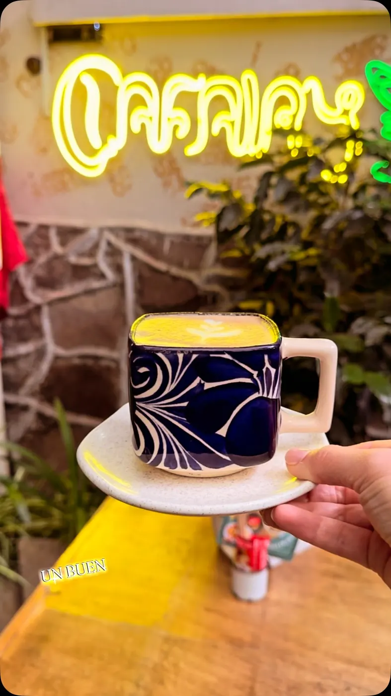 Taza de talavera azul frente al letrero de neón amarillo de Cafairy